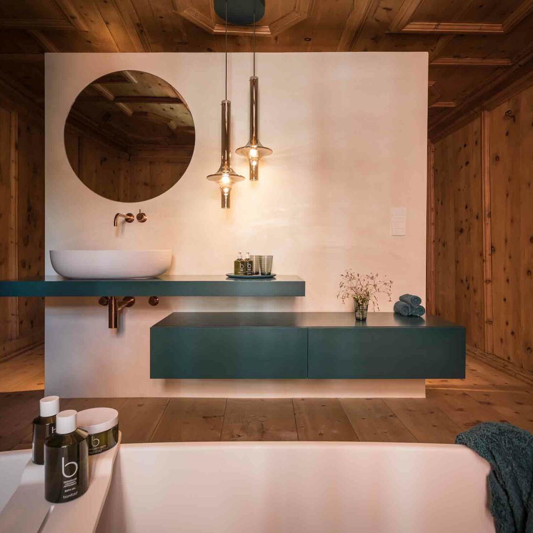 Holzverkleidung kombiniert mit modernen Elementen wie einem schwebenden Waschtisch, rundem Spiegel und stilvollen Hängelampen. Holzverkleidung kombiniert mit modernen Elementen wie einem schwebenden Waschtisch, rundem Spiegel und stilvollen Hängelampen.