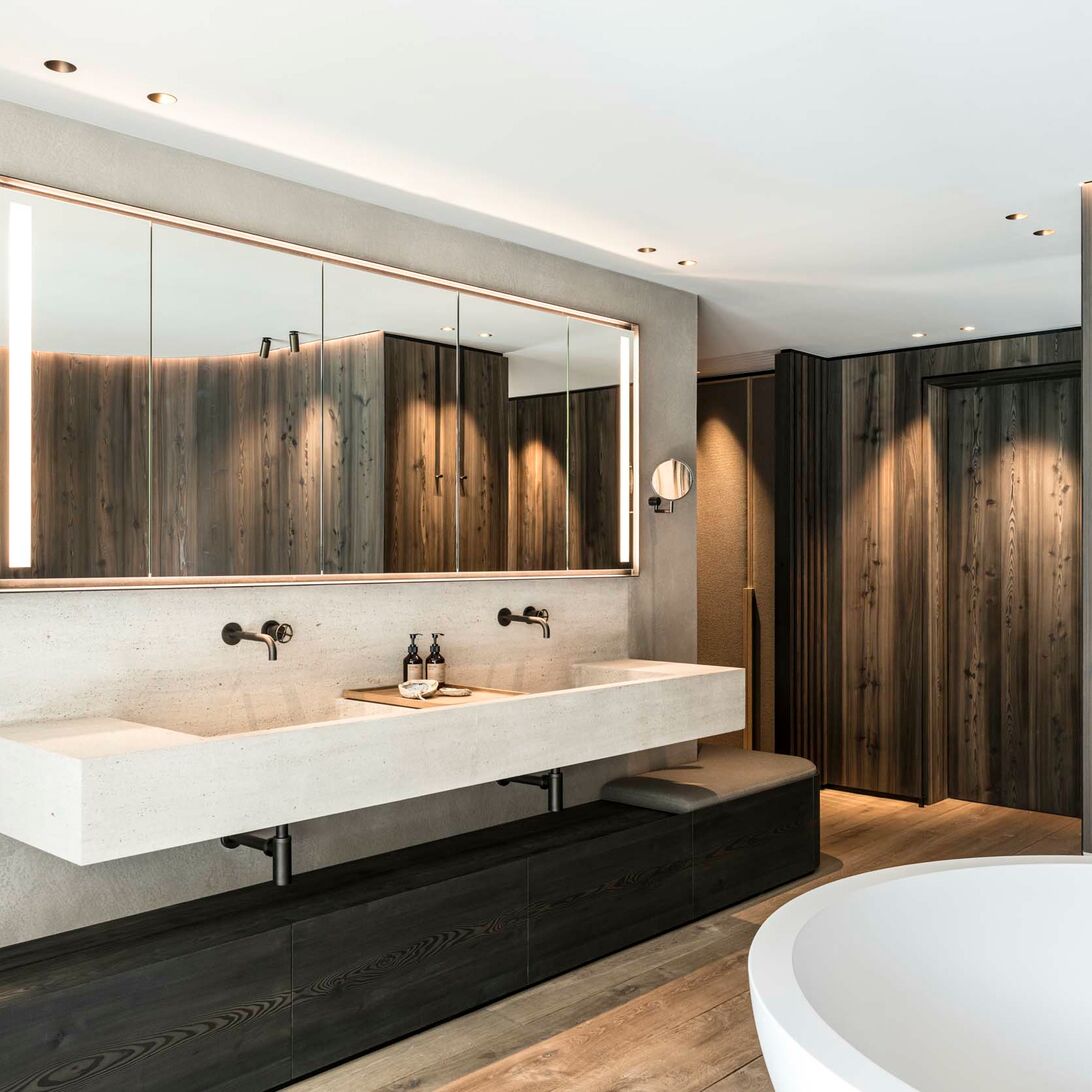 Modernes Badezimmer mit großem Spiegel, Doppelwaschbecken, Holzverkleidung, freistehender Badewanne und eleganter Beleuchtung. Luxuriöses Design. Modernes Badezimmer mit großem Spiegel, Doppelwaschbecken, Holzverkleidung, freistehender Badewanne und eleganter Beleuchtung. Luxuriöses Design.
